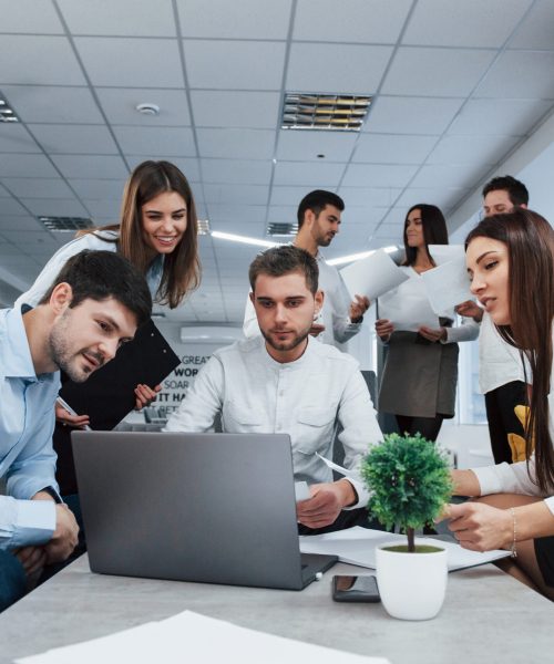 Working with laptop. Group of young freelancers in the office have conversation and smiling.